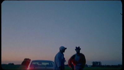 a man standing next to a horse next to a car