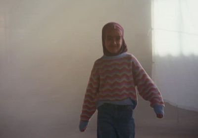 a young girl wearing a sweater and pants