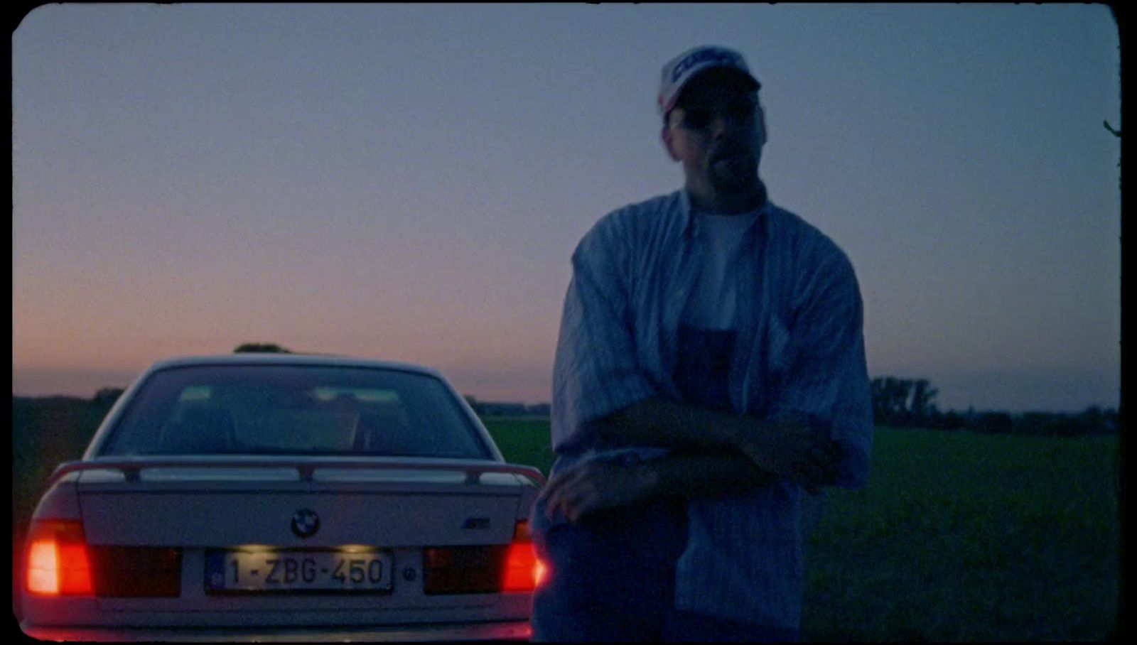 a man standing next to a car in a field