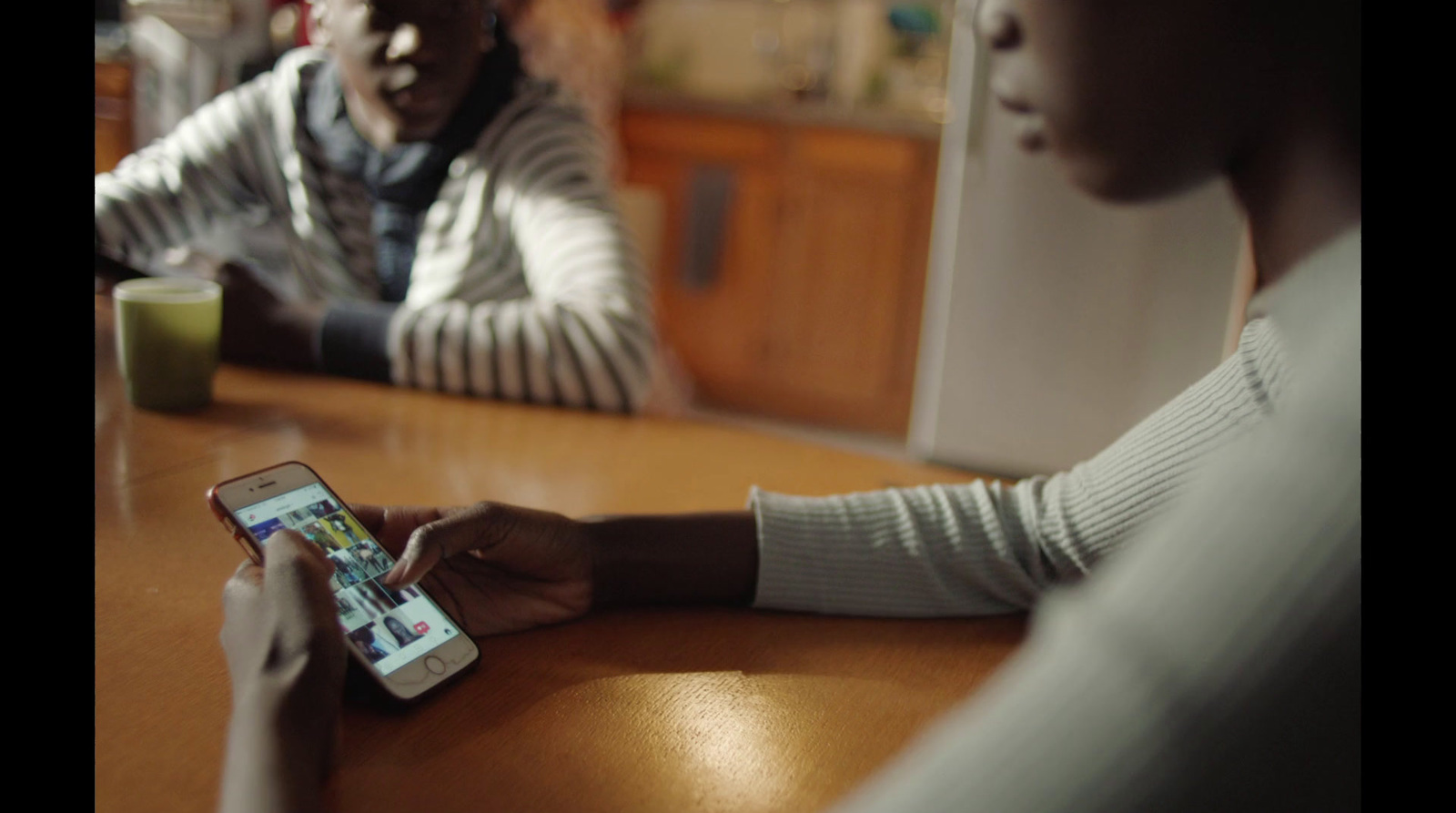 two people sitting at a table looking at a cell phone