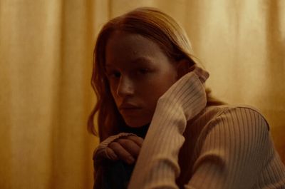 a woman with red hair is sitting in front of a curtain