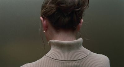 a woman wearing a turtle neck sweater and a pair of earrings