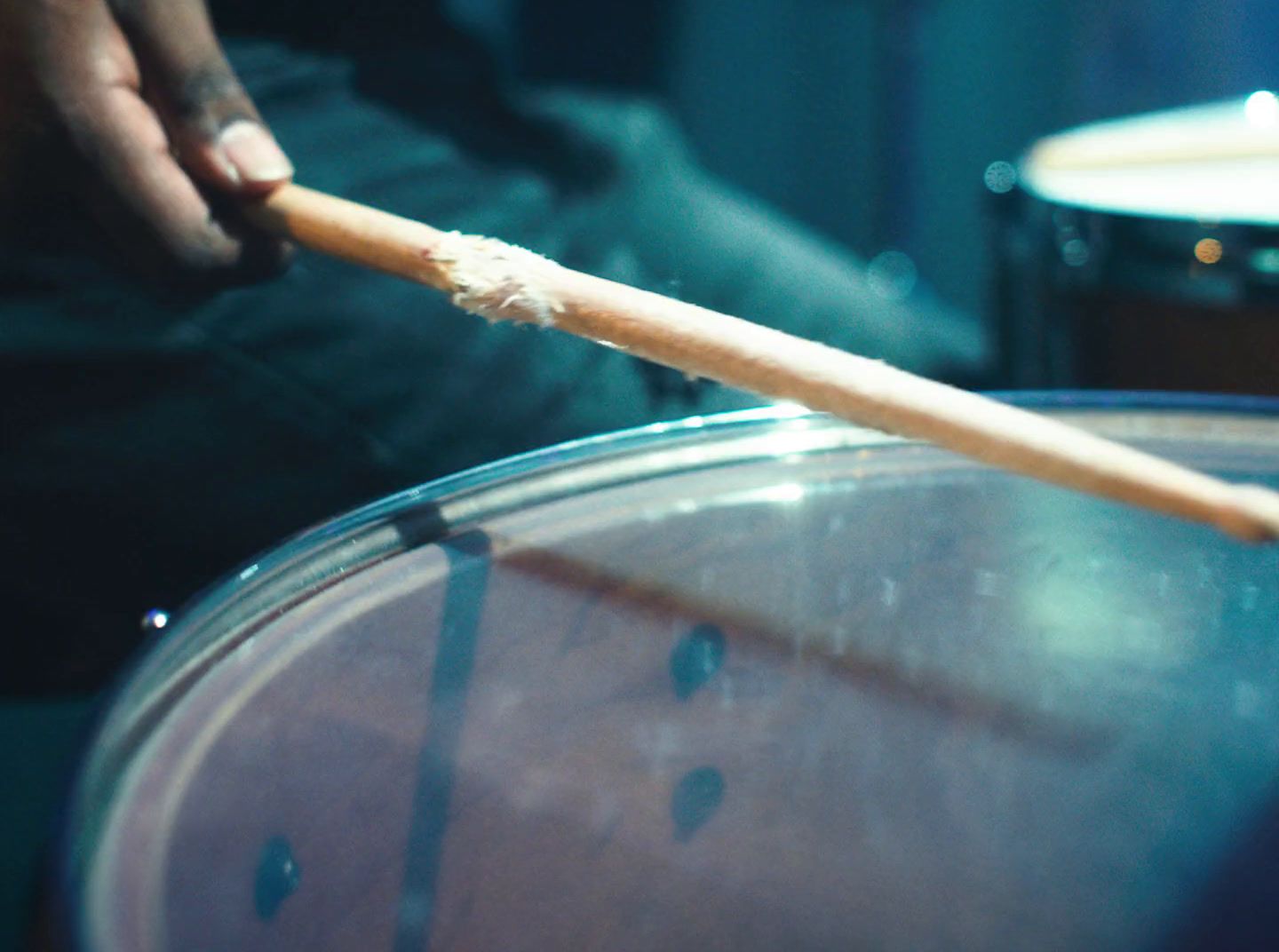 a person holding a wooden stick over a drum