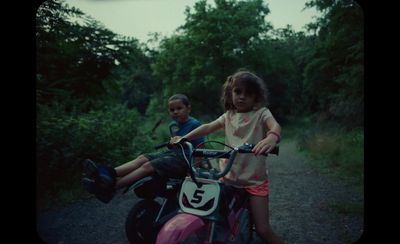 two children on a motorcycle on a dirt road