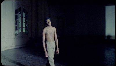 a man without a shirt standing in a dark room