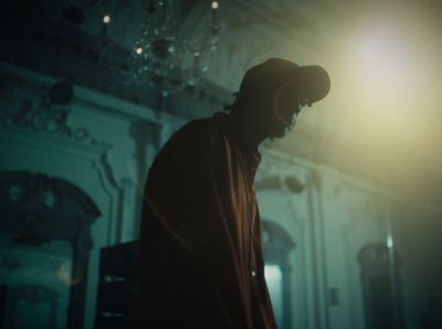 a man standing in a dark room with a hat on