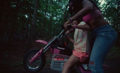 a woman riding on the back of a pink dirt bike