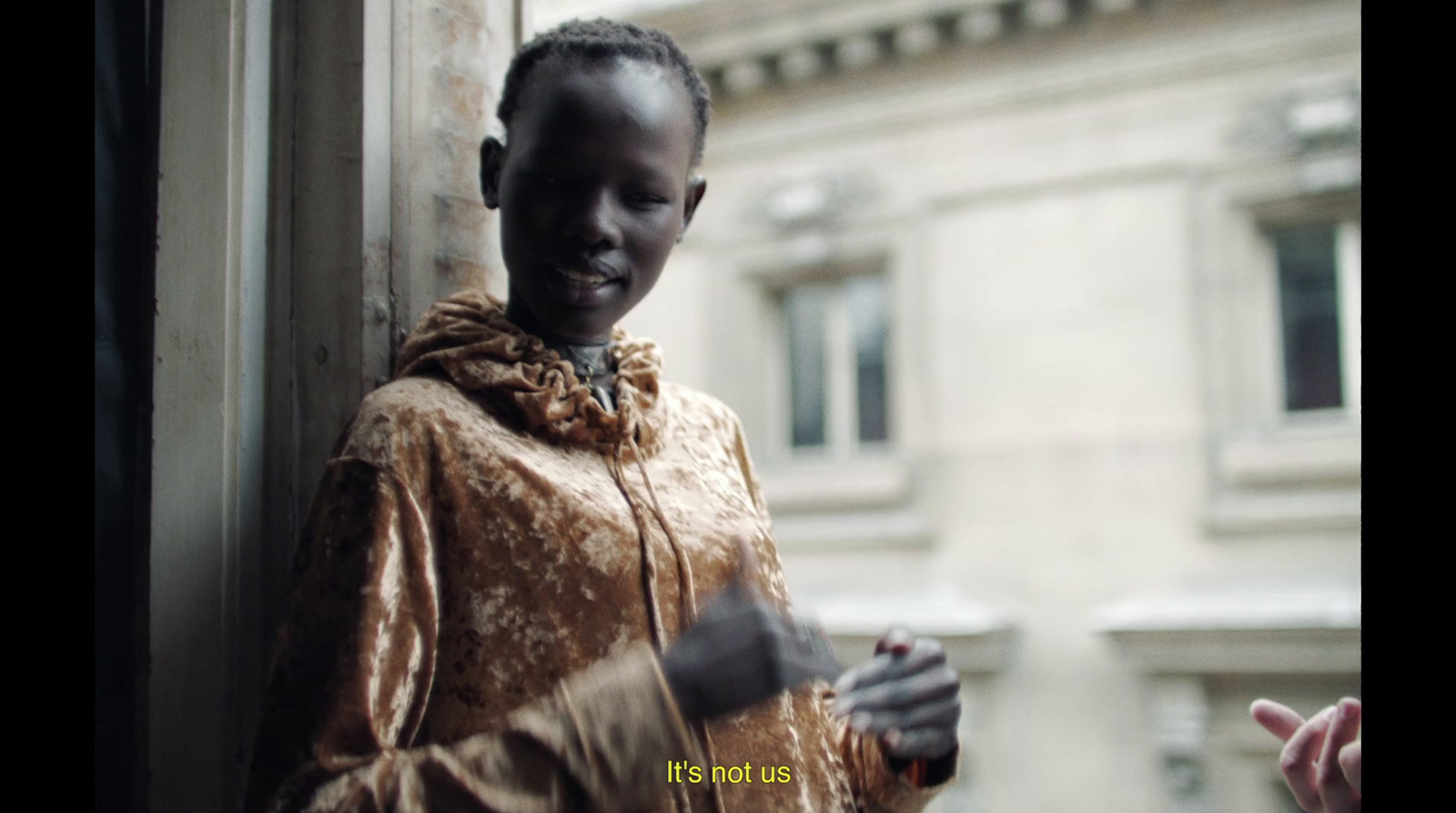 a woman standing next to a window holding a cell phone