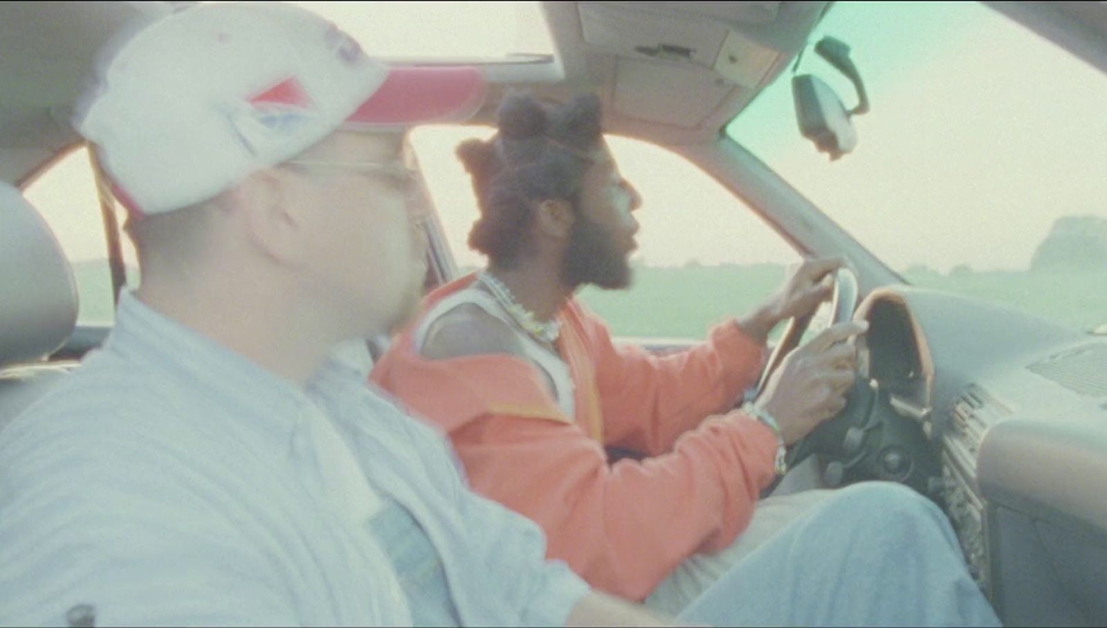 a man driving a car with another man sitting in the driver's seat