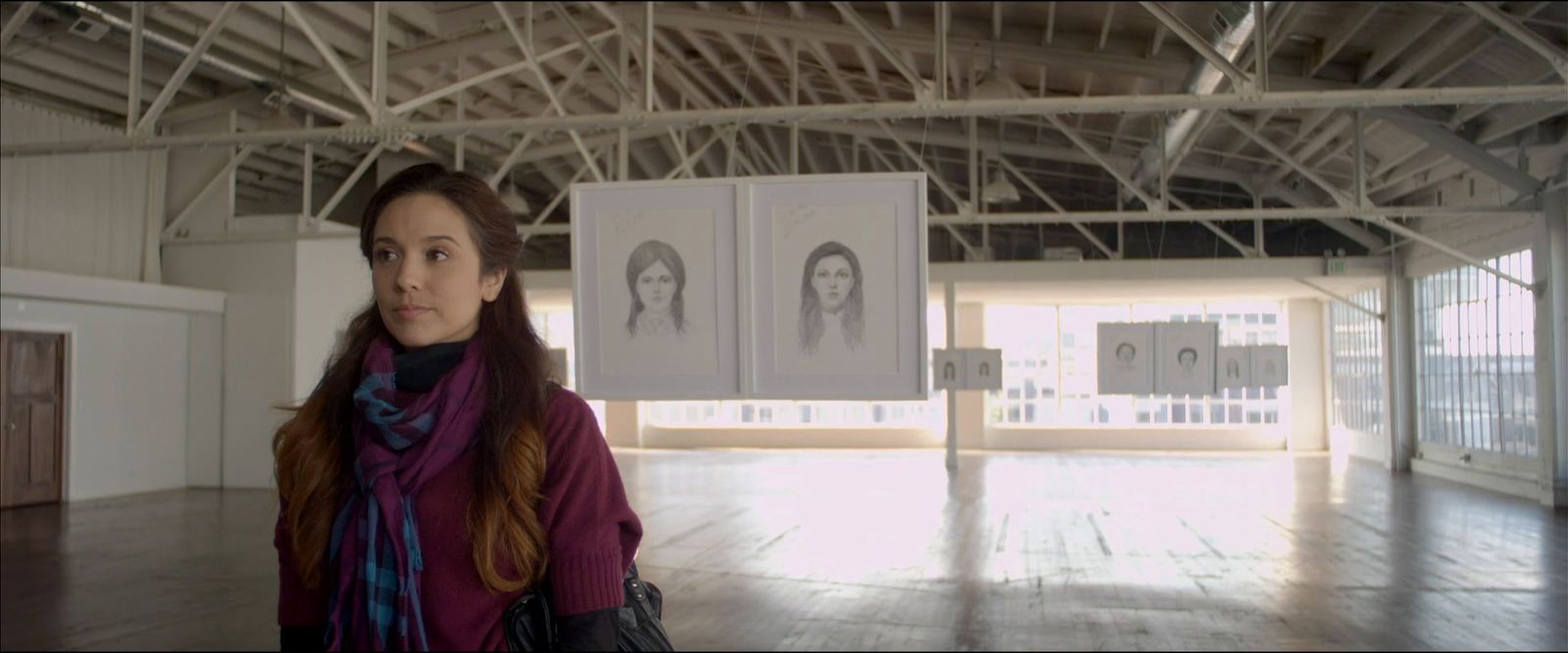 a woman standing in a large room with a picture hanging on the wall