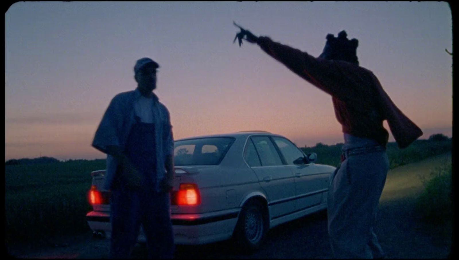 two men standing in front of a white car