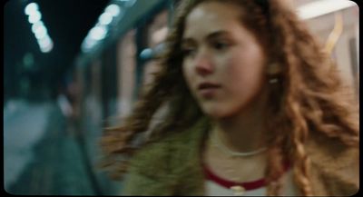 a woman with long hair standing next to a train