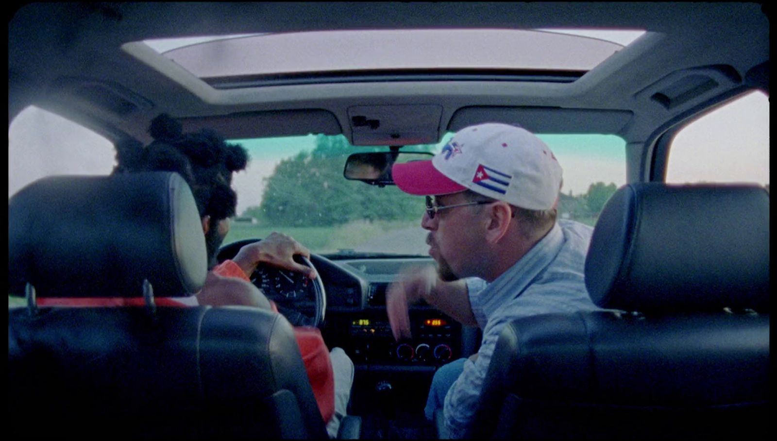 a man driving a car with another man in the passenger seat