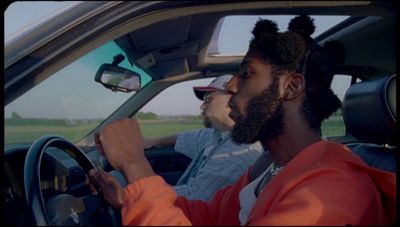 a man driving a car with another man in the passenger seat