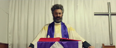 a priest is holding a purple and white present