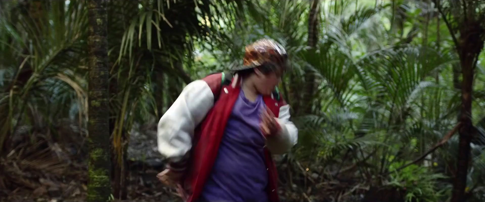 a woman walking through a lush green forest