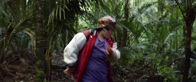 a woman walking through a lush green forest