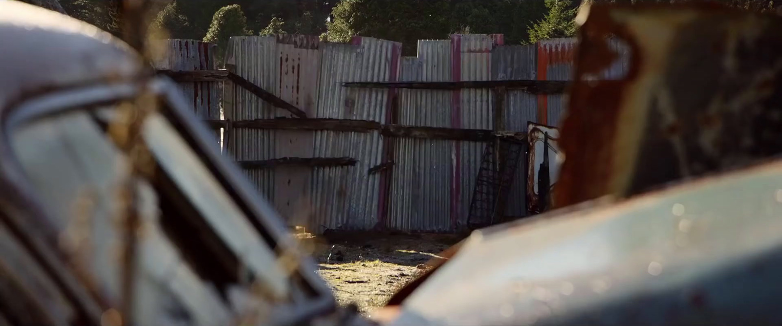 an old car parked in front of a wooden fence