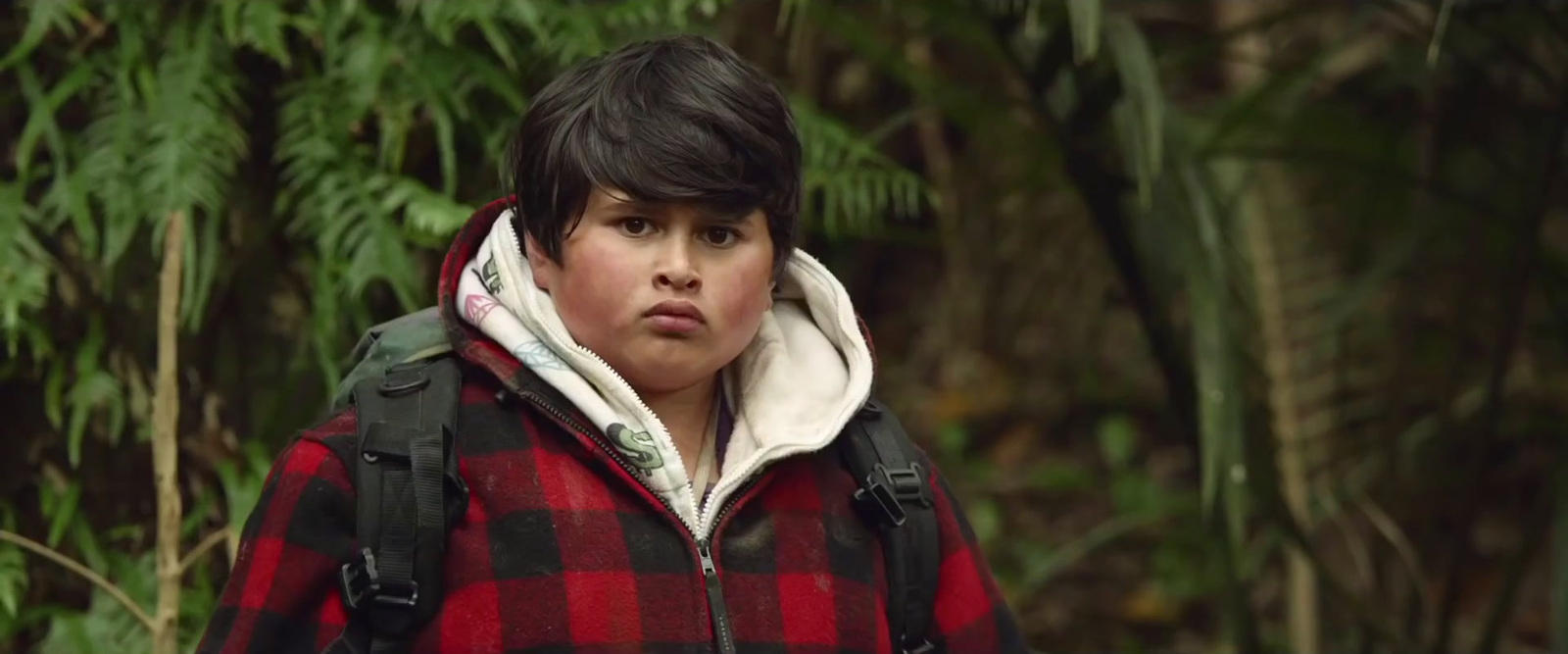 a young boy wearing a red and black plaid jacket