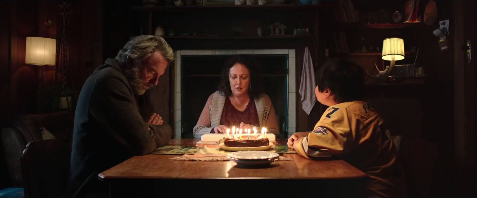 a woman sitting at a table in front of a cake with lit candles