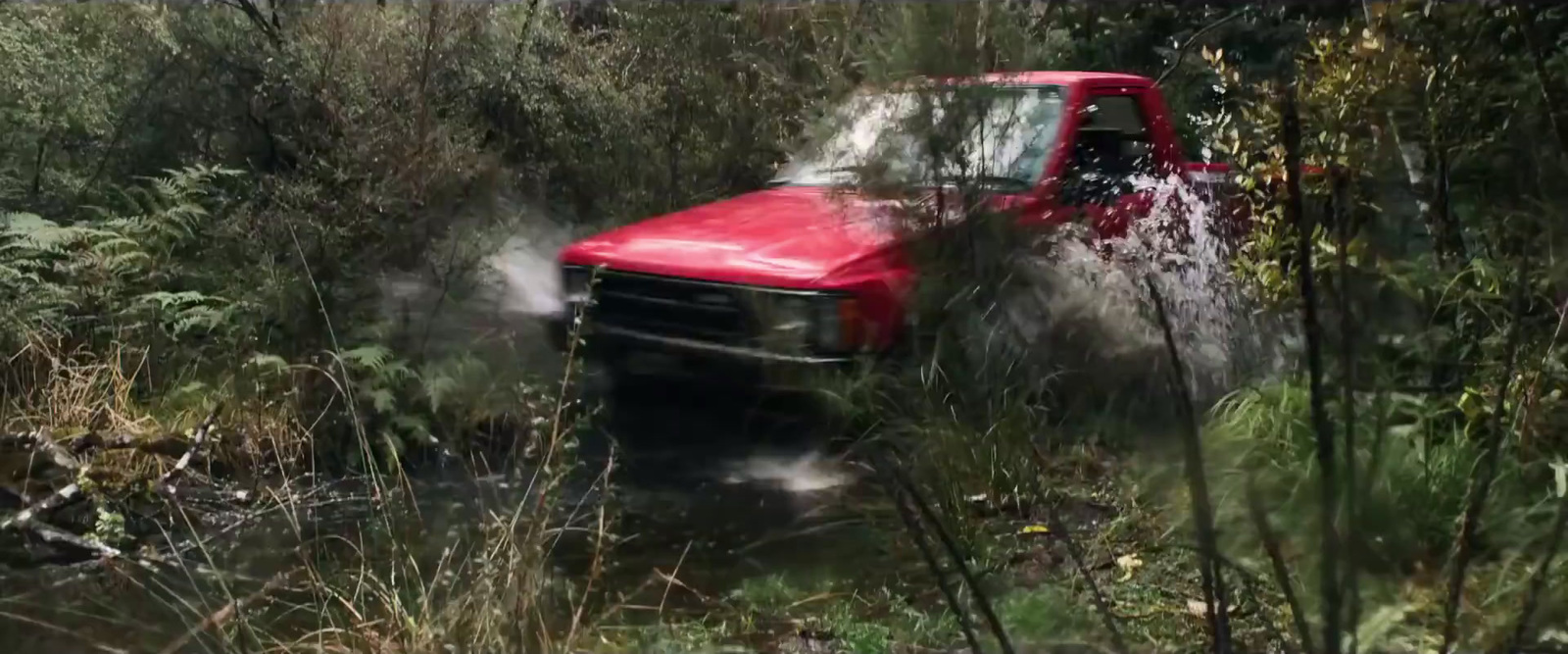 a red truck driving through a lush green forest