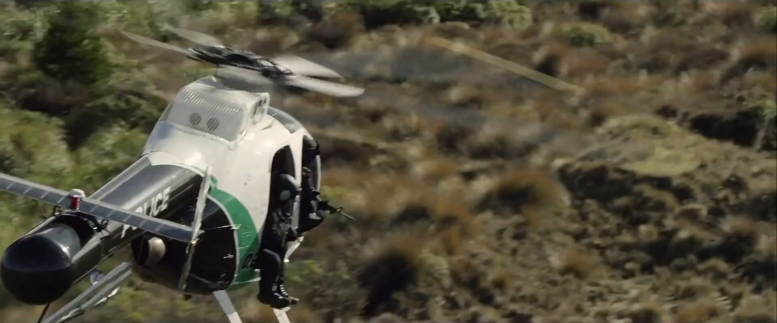 a helicopter flying over a lush green hillside