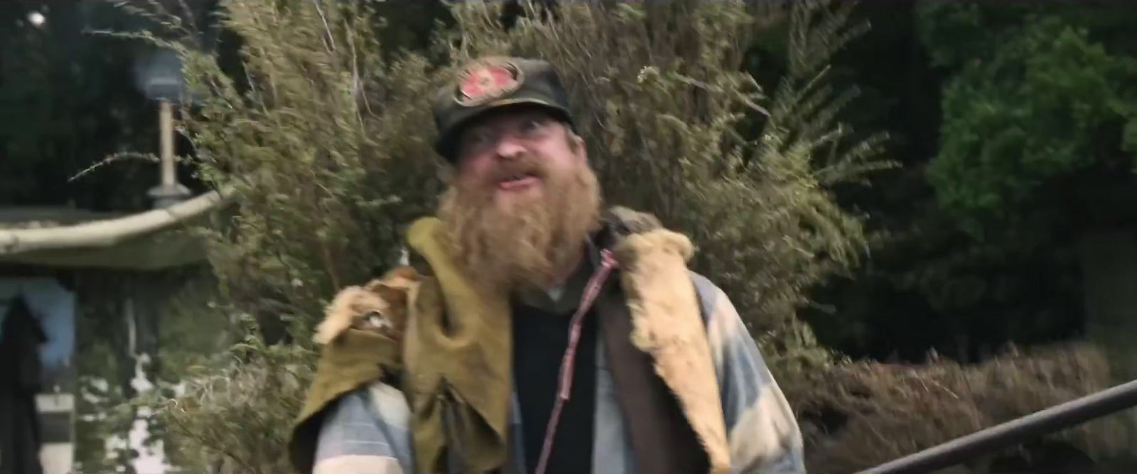 a man with a beard wearing a hat and vest