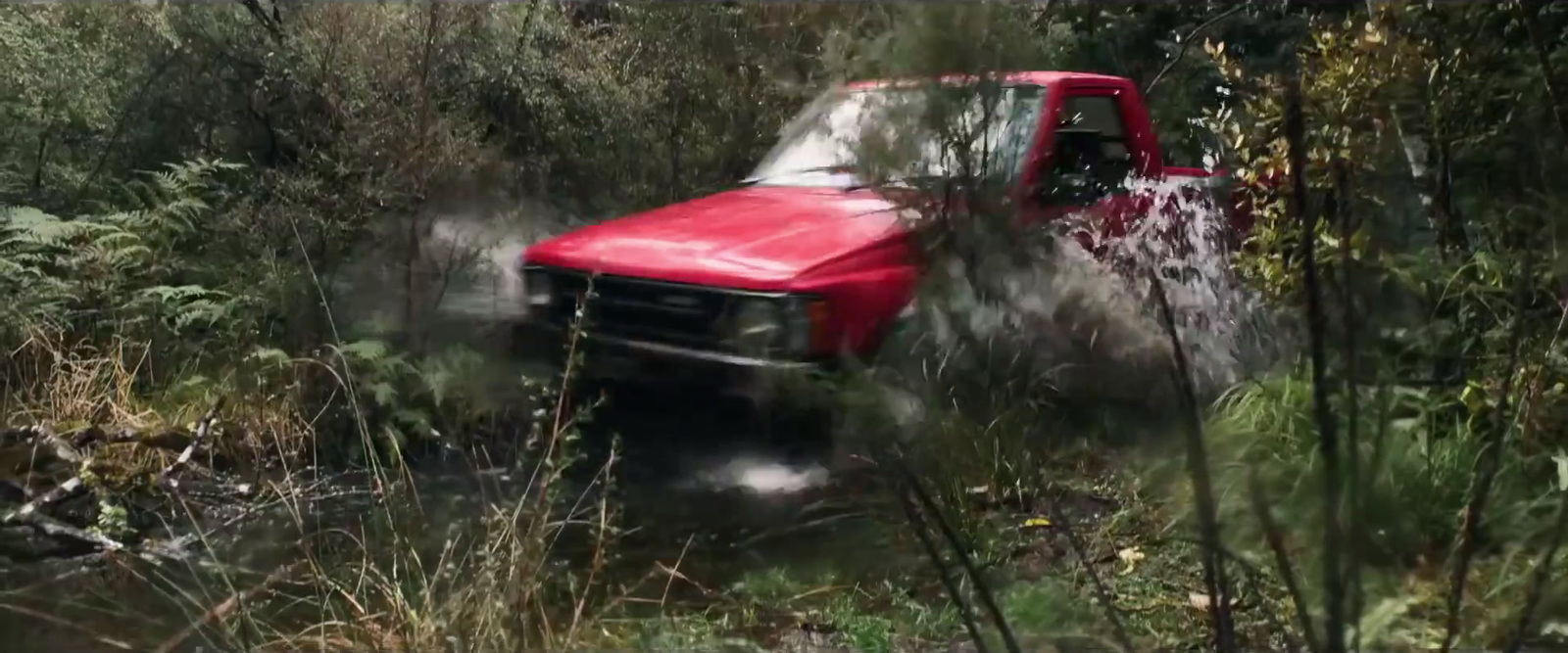 a red pick up truck driving through a forest