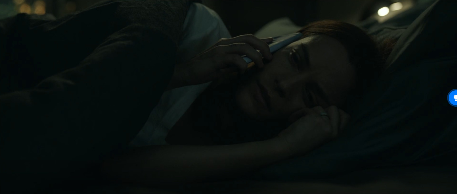 a woman laying in bed talking on a cell phone