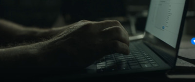 a person typing on a laptop computer with a twitter logo on the screen