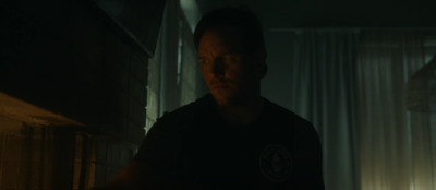 a man standing in a dark room next to a window