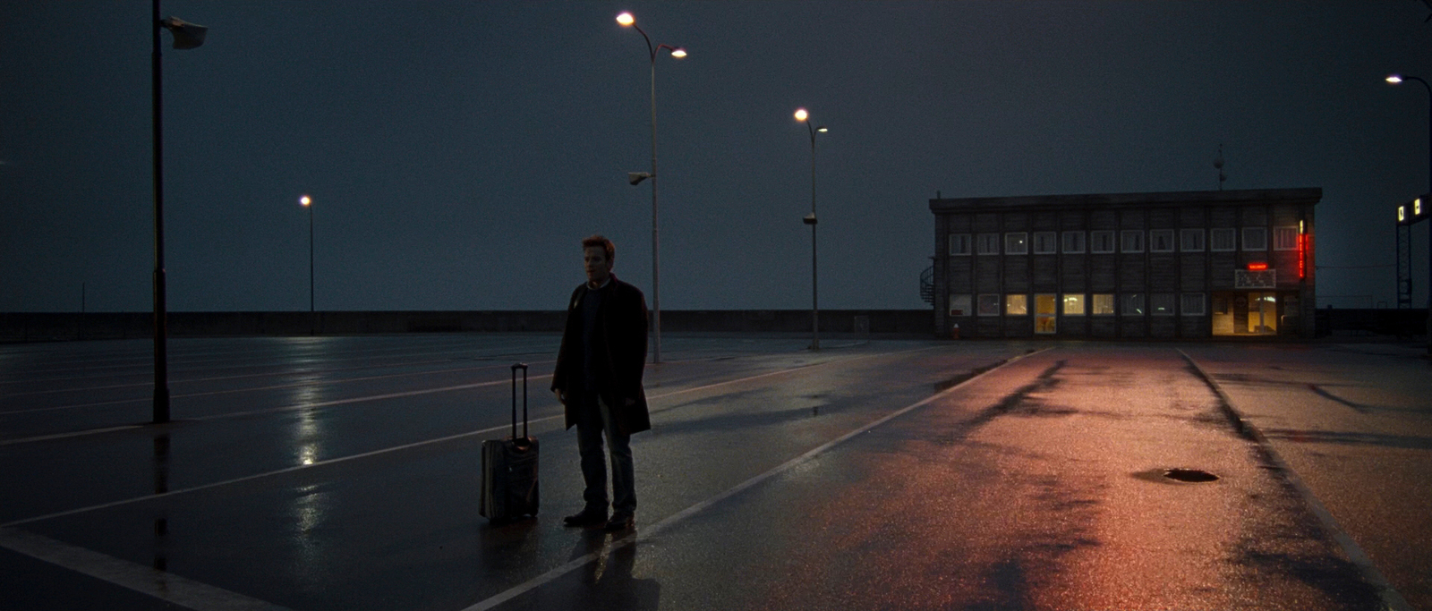 a man standing in a parking lot with a suitcase