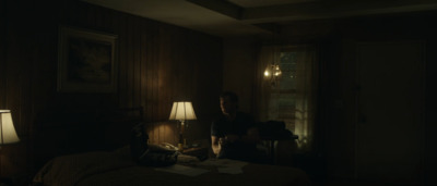 a man sitting on a bed in a dark room