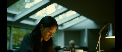 a woman sitting at a table writing on a piece of paper