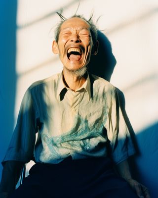 a man laughing while sitting in a chair