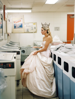 a woman in a dress and a crown sitting on a washing machine