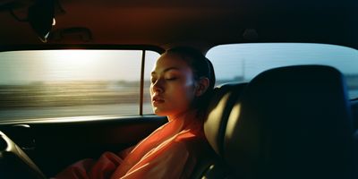 a woman sitting in a car with her eyes closed