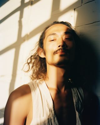 a man with long hair and a moustache standing in front of a wall