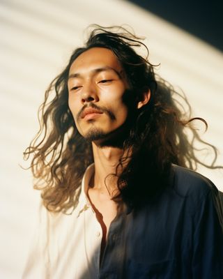 a man with long hair standing in front of a building