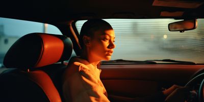 a woman sitting in a car with a steering wheel