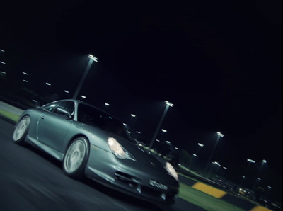 a silver car driving down a street at night