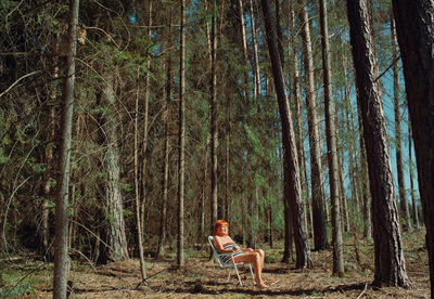 a woman sitting in a chair in the middle of a forest