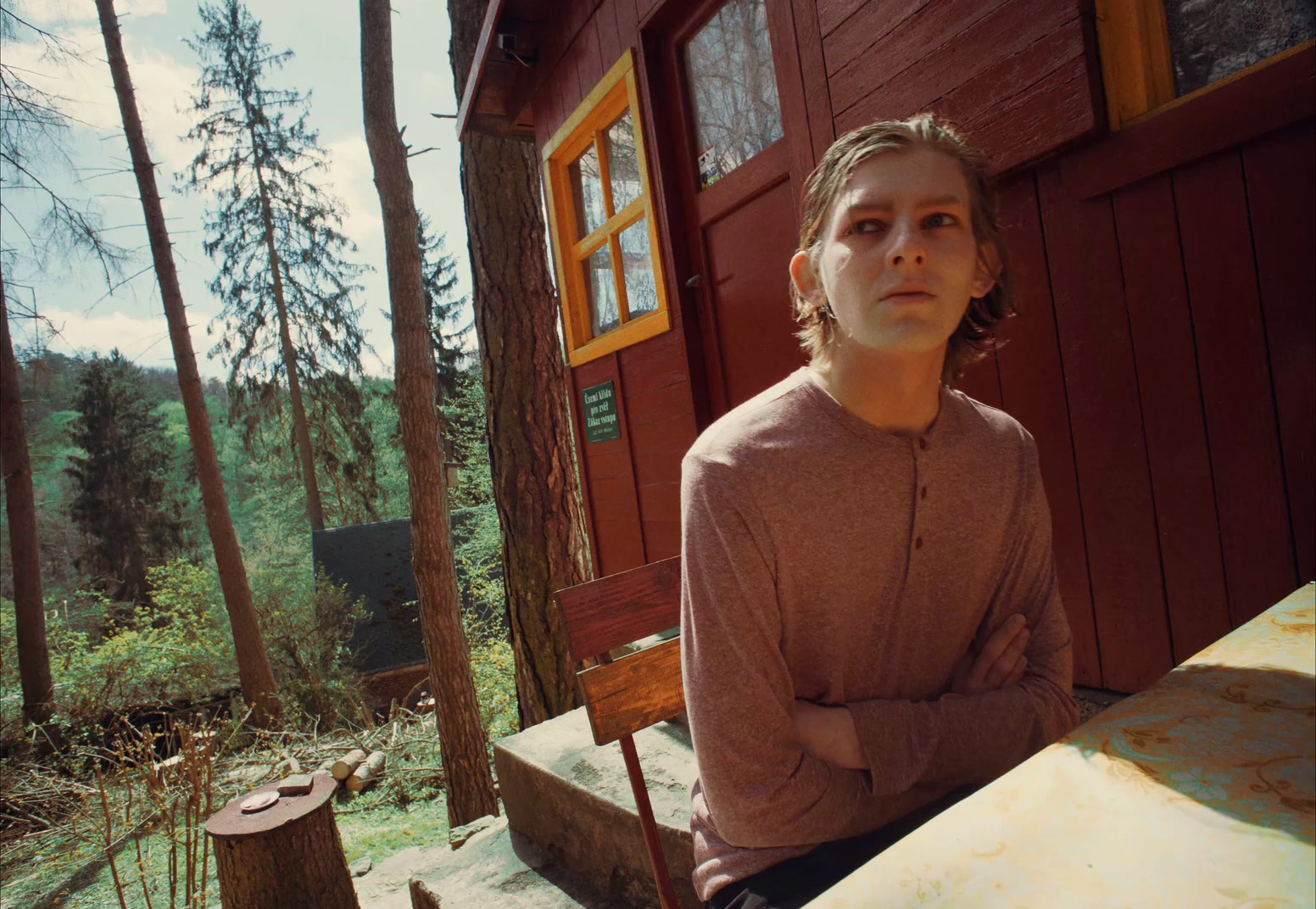 a woman sitting on a bench in front of a cabin