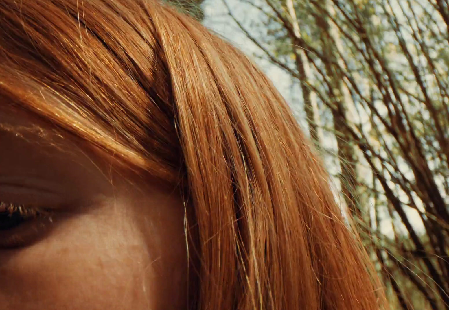 a close up of a woman's face with trees in the background