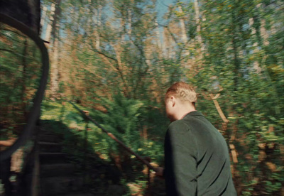 a man standing in front of a forest filled with trees