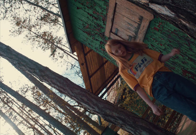 a girl standing on a tree branch in front of a building