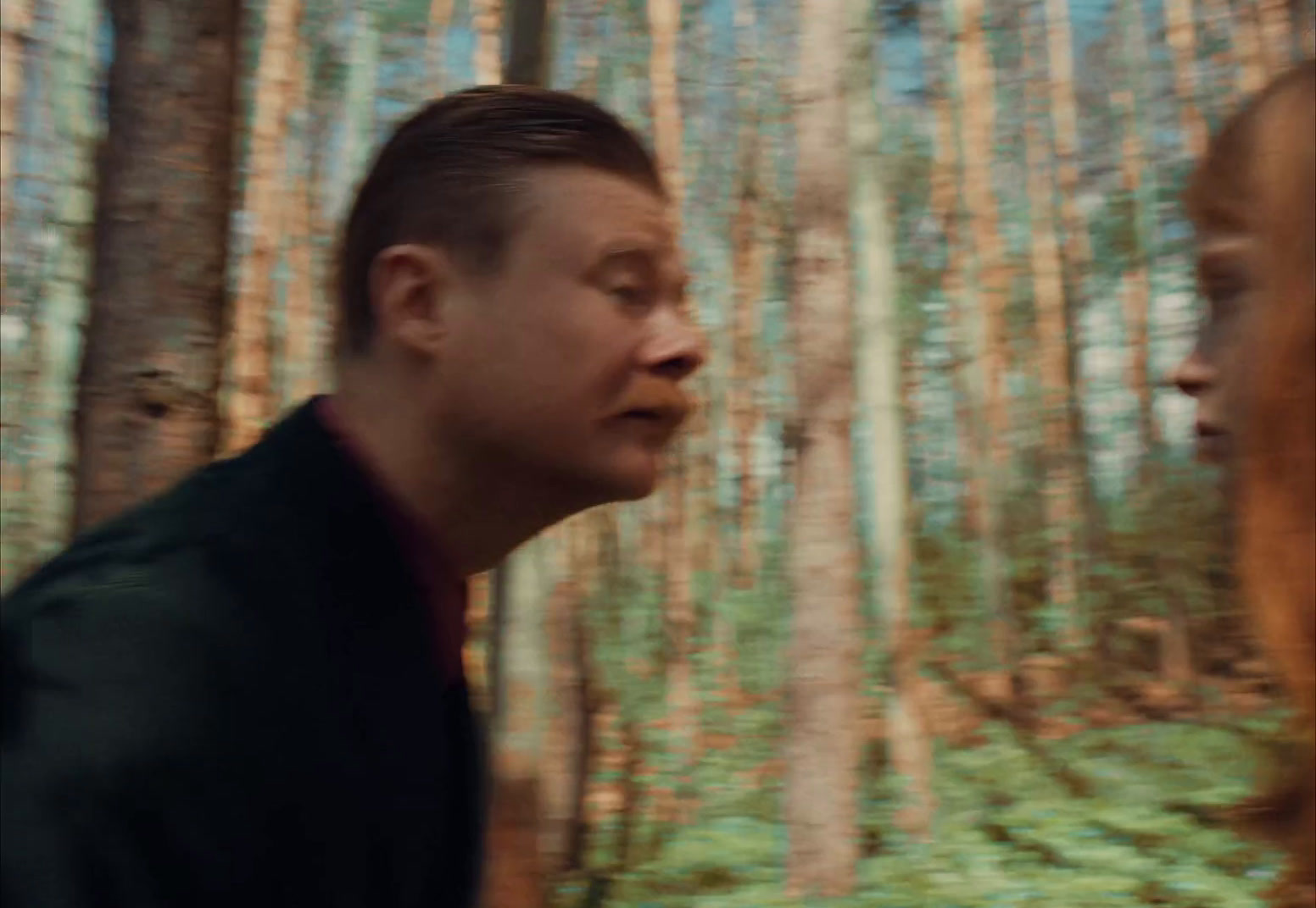 a man and a woman walking through a forest