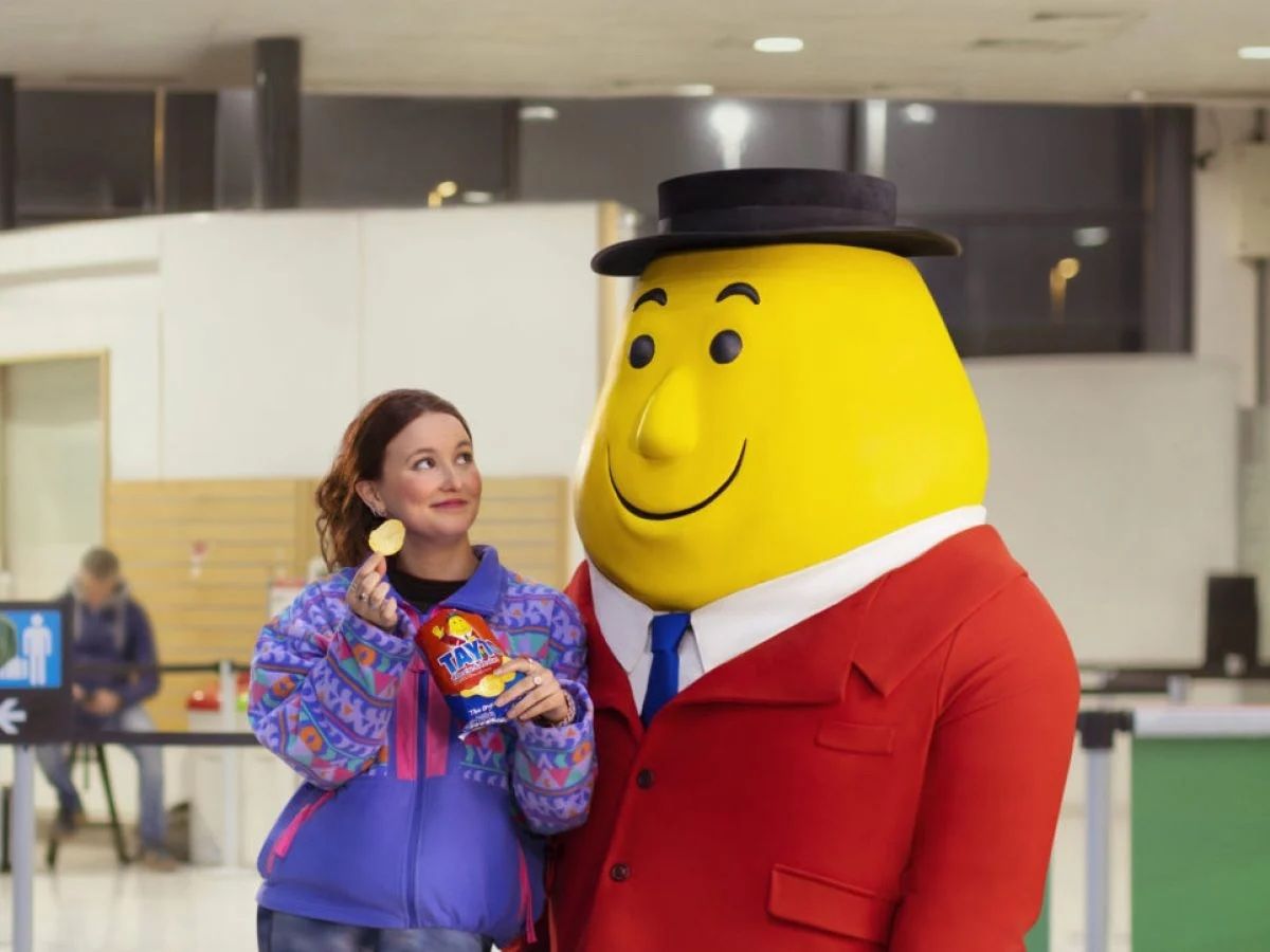 a woman standing next to a giant yellow cartoon character