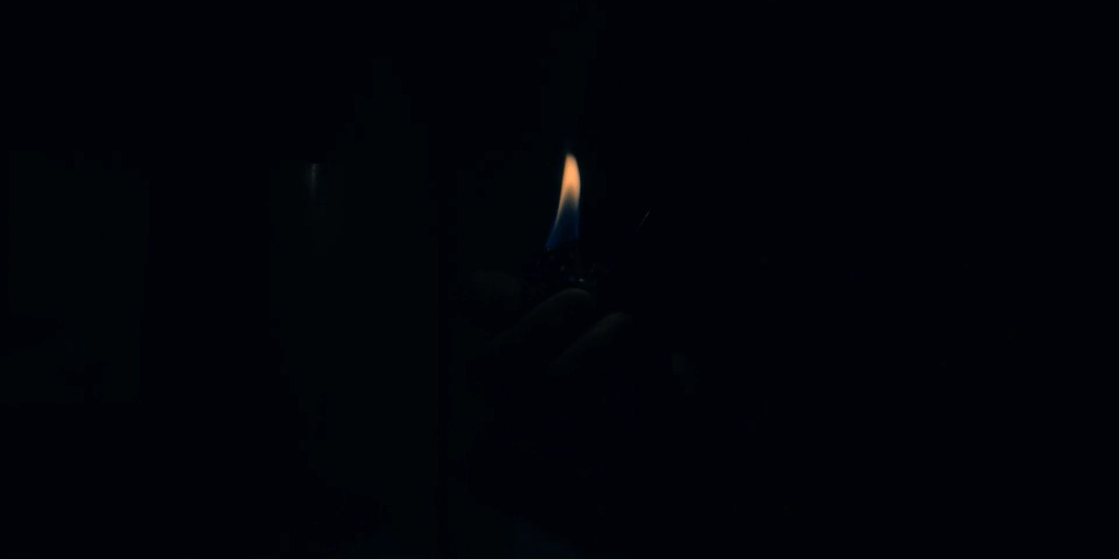 a person holding a lit candle in the dark