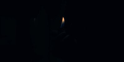 a person holding a lit candle in the dark